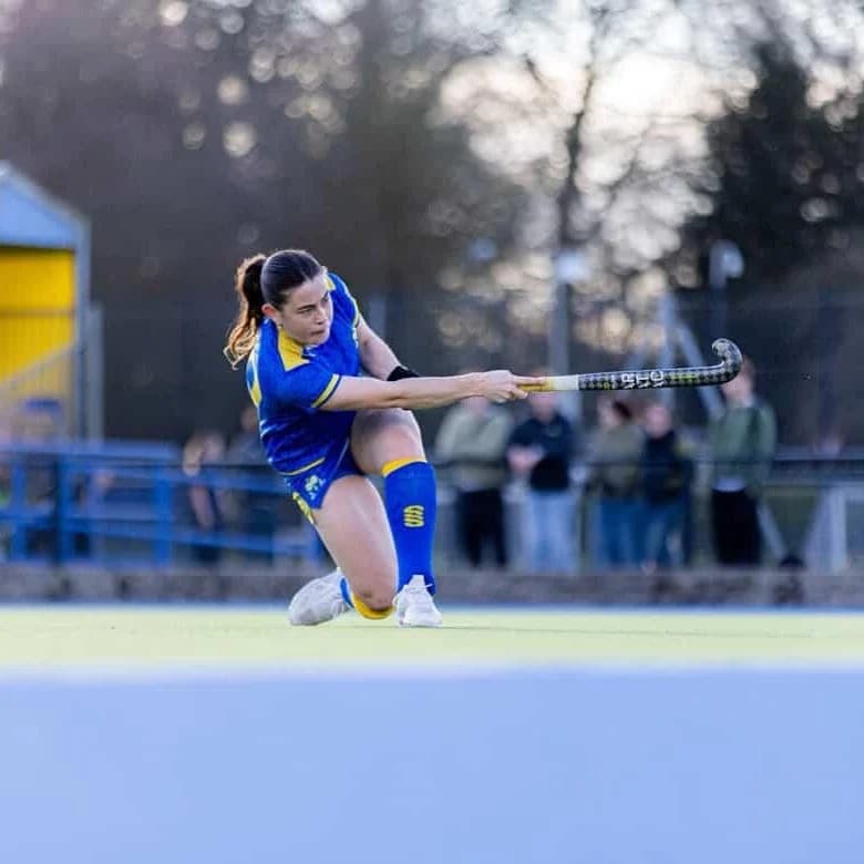 Hockey player striking the ball from a low stance during a match