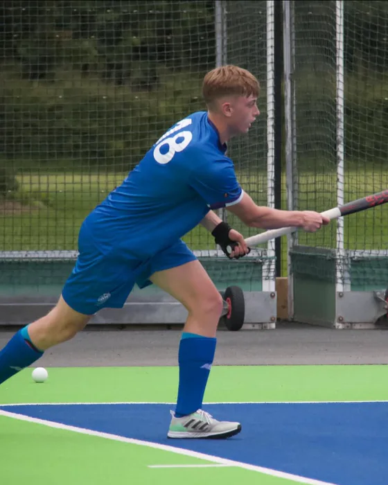 Daniel Smith playing a pass on a green and blue hockey pitch.