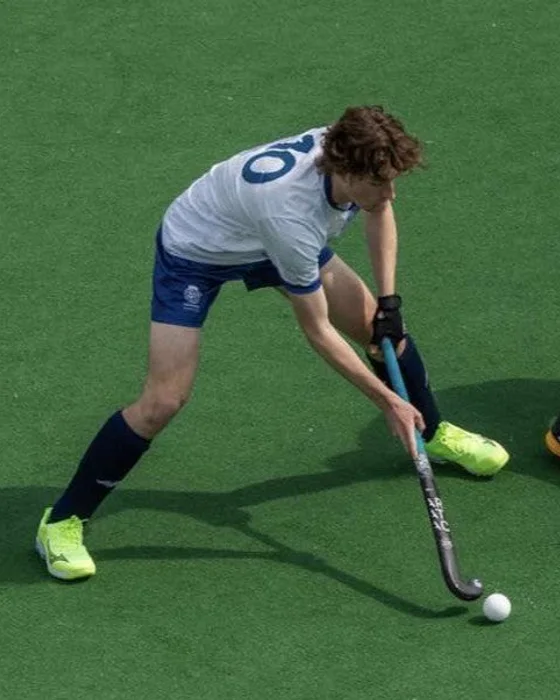 Harry Hattam controlling the ball on a green hockey pitch.
