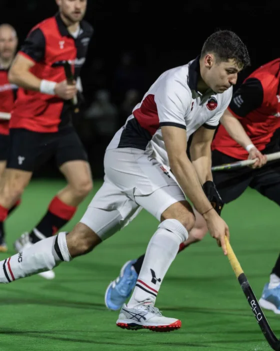 Karan Sofat controlling the ball under pressure in an indoor hockey match.