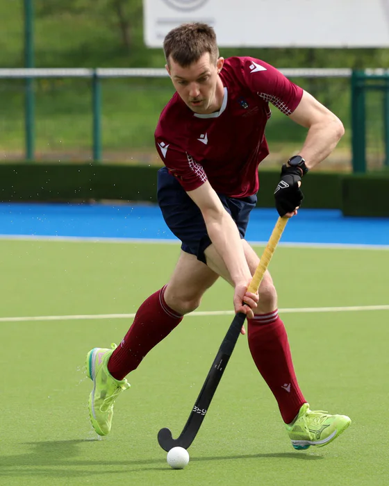 Tommy Orr moving the ball forward on a green hockey pitch.